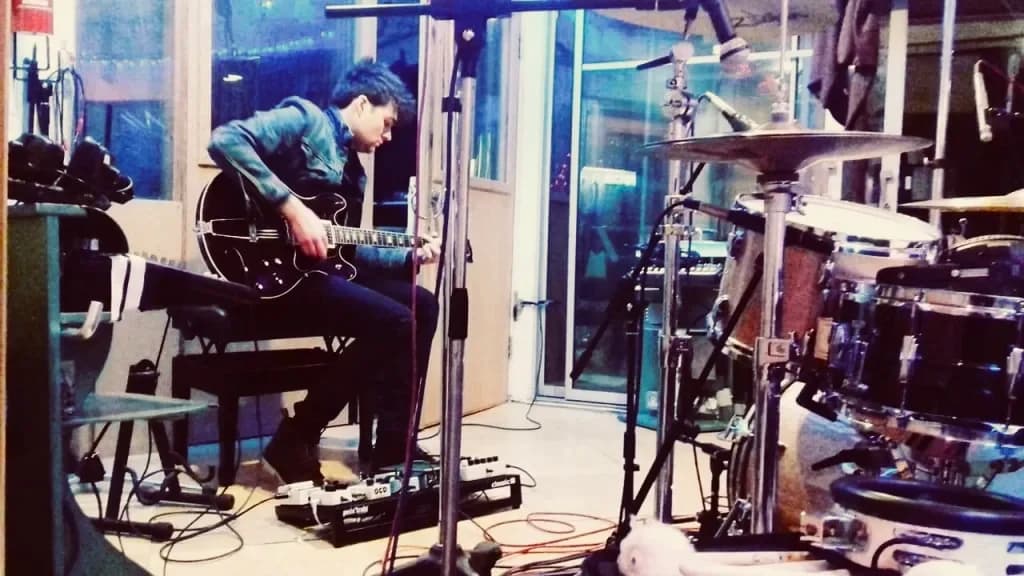 Conor Mangan playing an electric guitar in a recording studio
